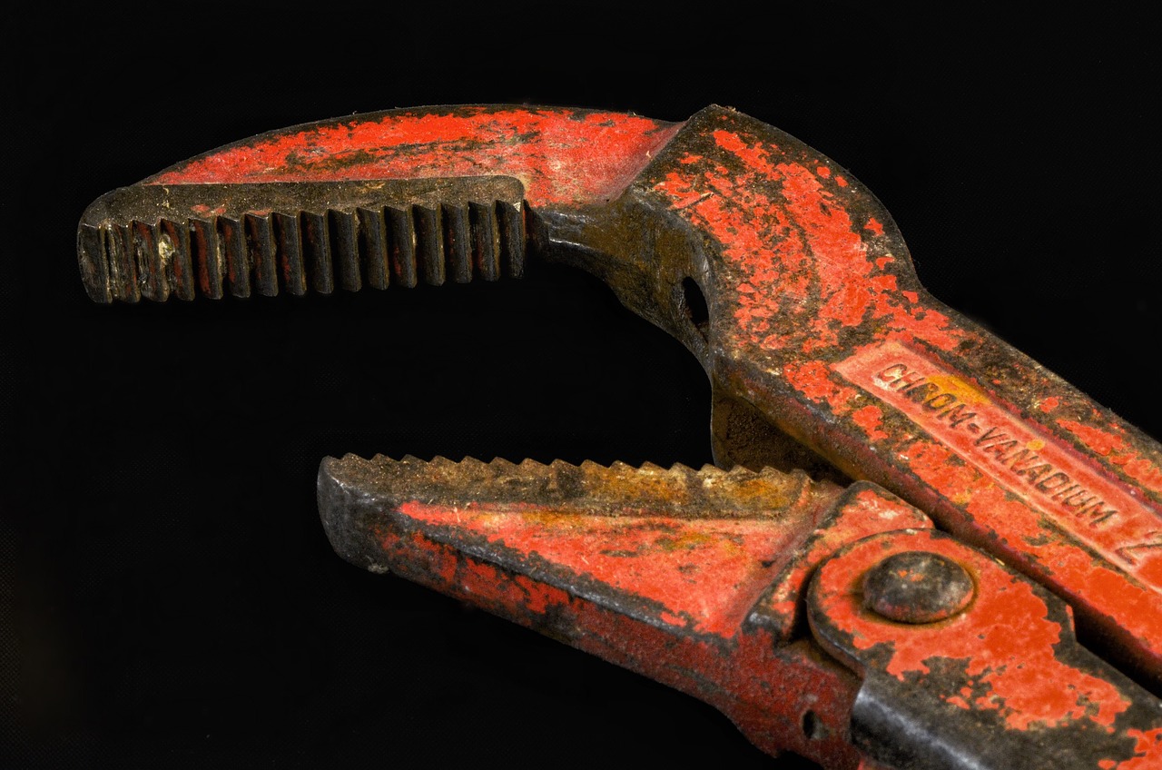 Red pipe wrench, paint worn to bare metal, on a black background